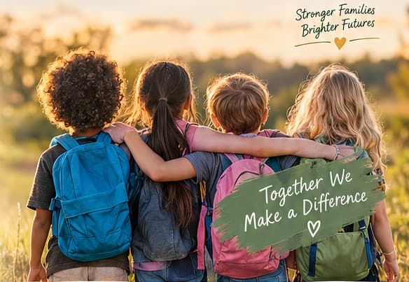 Four children with backpacks walking arm in arm through a sunny field